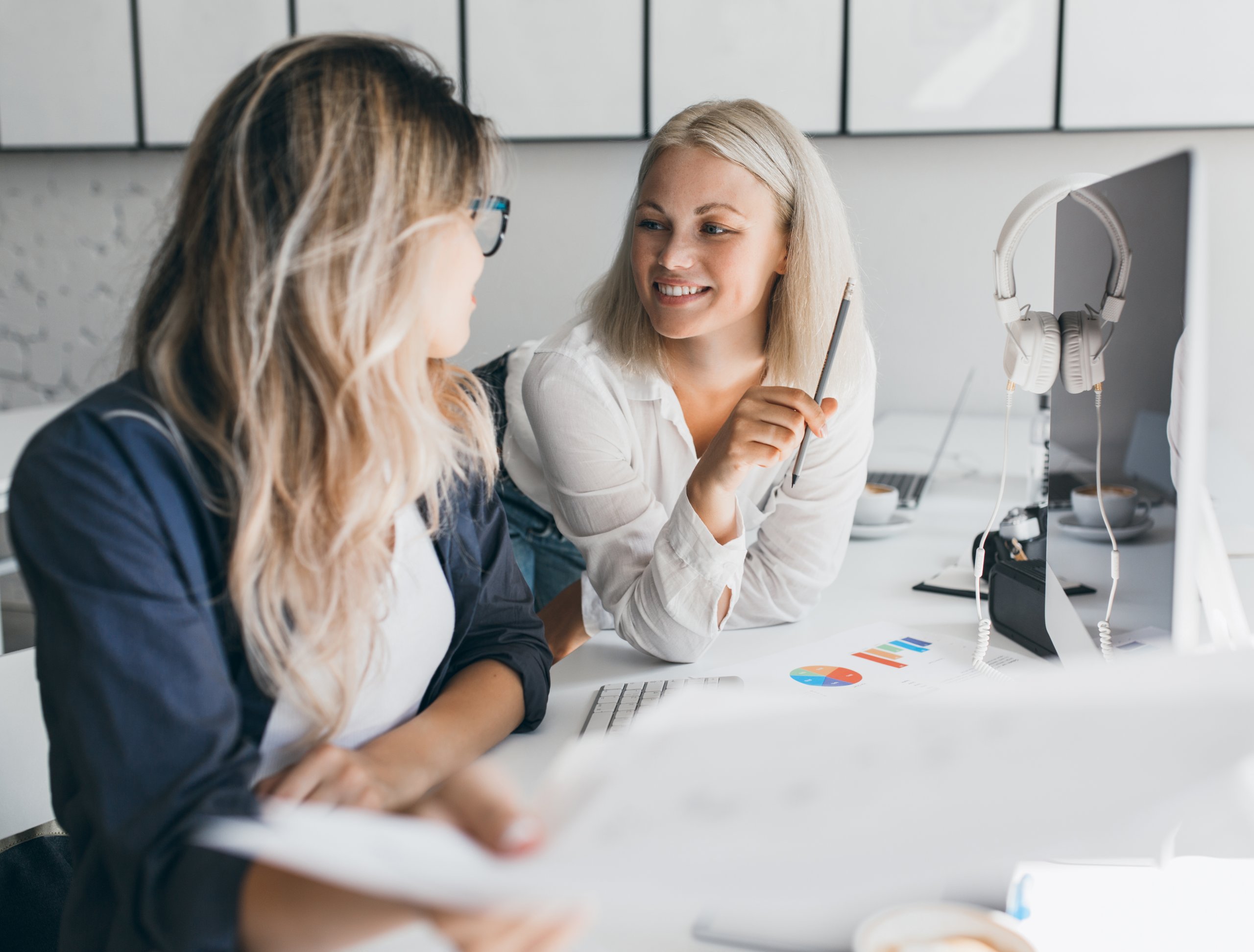 amadeus Leistung 5 Zwei Mitarbeiterinnen von amadeus entwickeln gemeinsam kreative Ideen und besprechen Inhalte aus den Leistungsbereichen Design Strategie und Markenkommunikation am Arbeitsplatz mit digitalen Tools