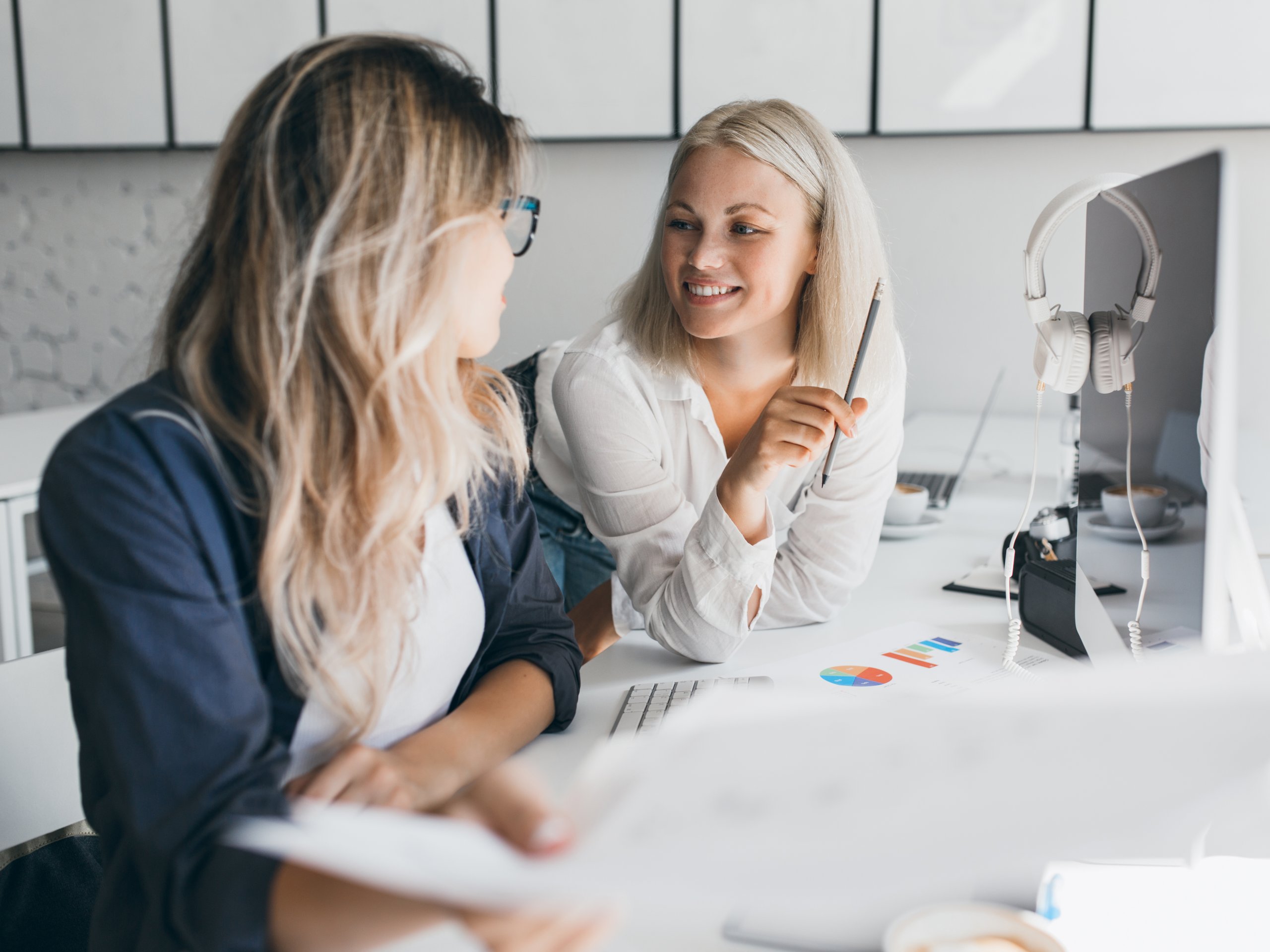 Zwei Mitarbeiterinnen von amadeus entwickeln gemeinsam kreative Ideen und besprechen Inhalte aus den Leistungsbereichen Design Strategie und Markenkommunikation am Arbeitsplatz mit digitalen Tools