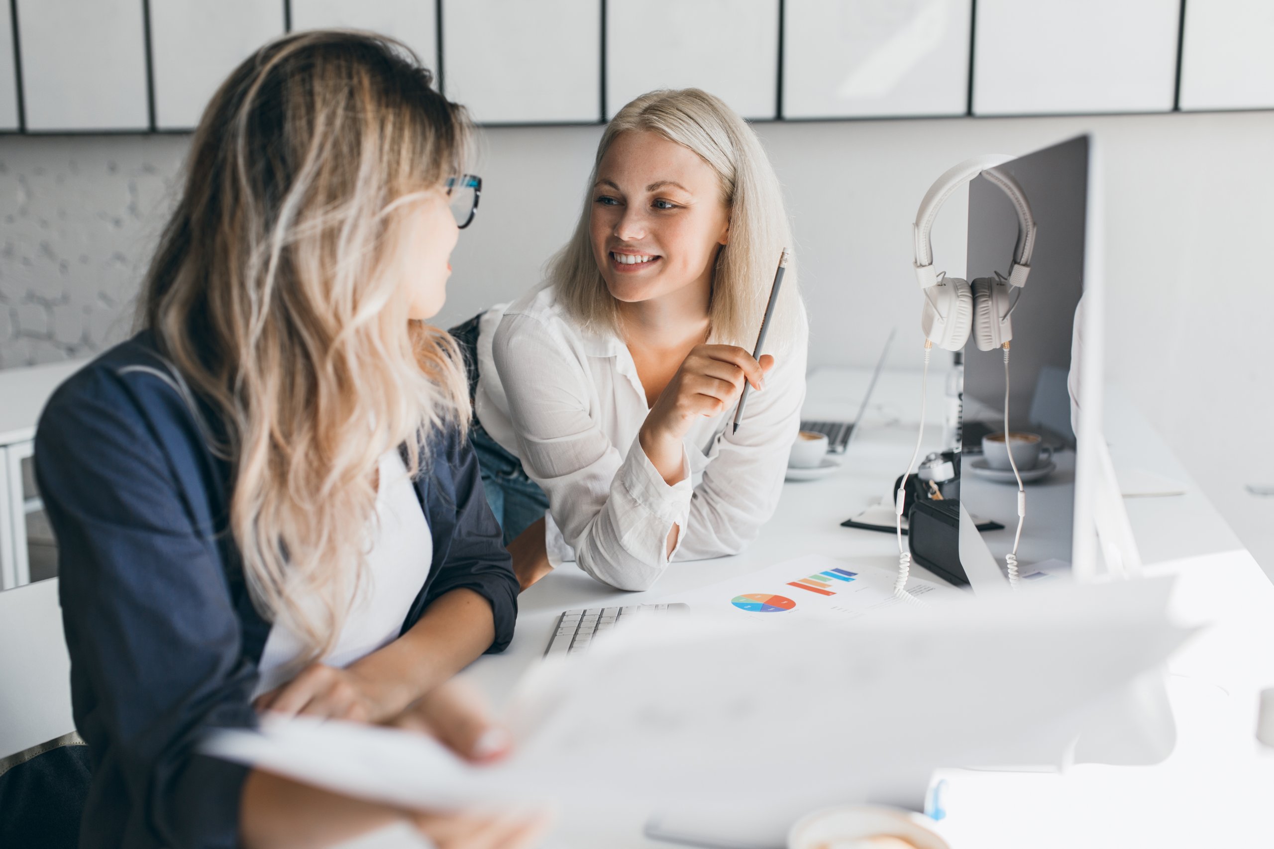 Zwei Mitarbeiterinnen von amadeus entwickeln gemeinsam kreative Ideen und besprechen Inhalte aus den Leistungsbereichen Design Strategie und Markenkommunikation am Arbeitsplatz mit digitalen Tools