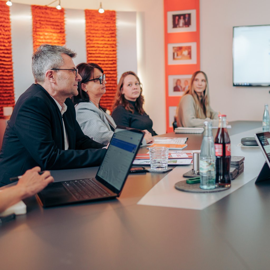 Personen unterhalten sich gemeinsam bei einem Marketing-Meeting in einem Besprechungsraum.